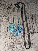Five necklaces laid out on floor carpet, showing variety from sterling silver chains to handmade colorful beaded necklaces.