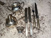 Full view of all sterling silver serving pieces including sugar bowl, creamer, wine stopper, carving knife, carving fork, and butter knives.