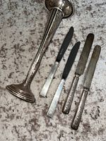 Sterling silver vase with four sterling silver knives arranged beside it, displaying the vase and flatware together.