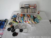 Full view of assortment of camera lens filters in boxes and loose filters spread on table.