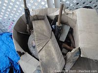 Box containing a bit brace, various hand saw blades including a Stanley miter saw blade, and several handles and metal tools, all worn and heavily used.