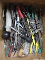 Box filled with packed hand tools including pliers, screwdrivers, wire brush, tin snips, and more.