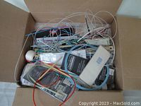 Photo of a full box with tangled cables, yarn, and packages inside.