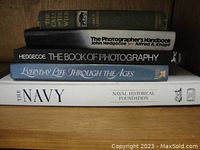 Stack of 5 books showing titles including The Call of the Wild, The Photographer's Handbook, The Book of Photography, Everyday Life Through the Ages, and The Navy.