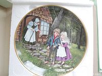 Collector’s plate featuring Hänsel and Gretel scene with children and gingerbread house in forest, displayed in styrofoam packaging.
