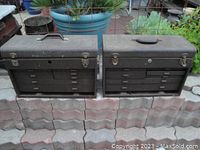 Two vintage metal machinist toolboxes positioned outdoors showing front and top sides with multiple drawers. Both toolboxes are worn and missing front door closures; one is missing the lock.