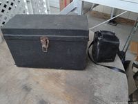 Photo of two black carrying cases: one large with metal latch, and a smaller box with strap.