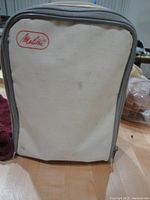 Front view of soft beige carrying case with Melita in red letters