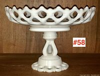 Side view of white milk glass pedestal server showing open lattice edge and sculpted base.