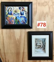 Overall view of two framed art pieces hung on wooden wall, showing size difference and framing style.