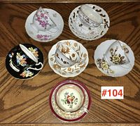 Top-down view of all six teacups with matching saucers arranged in a circle on wooden table