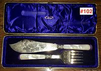 Top view of antique fish servers in original blue velvet-lined box showing knife and fork with sterling blades and mother of pearl handles.