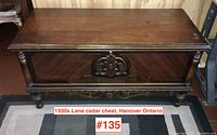 Front view of the cedar chest showing decorative carved wood panel and turned columns