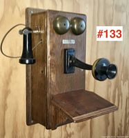 Angled side view of oak telephone showing shelf, bells, mouthpiece and receiver.
