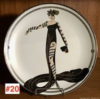 Front view of the Art Deco style decorative porcelain plate showing full figure design of a woman in black gown with gold and white accents.