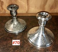 Pair of two Birks silver plate candlesticks positioned side by side on a wooden surface. One candlestick is polished, the other is tarnished. Both have engraved floral and scroll designs and a letter B monogram on the base.