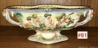 Full view of oval figural decorated Italian ceramic console bowl showing cherubs and floral motifs along the side.