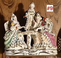 Full view of the German fine porcelain figurine group showing two seated women and one standing man around a table.