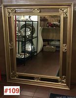 Full image of the large framed mirror showing its reflective surface and detailed gold frame with ornate elements.