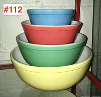 Four Pyrex mixing bowls nested inside each other, showing different exterior colors and white interiors.