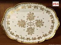 Full front shot of dresser tray showing detailed gold floral and scroll design on white porcelain.