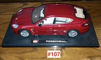 Front and side view of red Porsche Panamera diecast model on black display base showing detailed exterior and wheels.