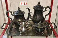 Full tea and coffee set including tray, teapot, coffee pot, creamer, and sugar bowl on display.