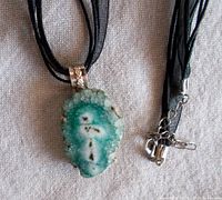 Front view of the druzy crystal pendant showing its natural sparkling surface and silver-toned bezel on the black silk cord.