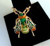 Front view of the colorful honey bee brooch showing enamel and gold-tone metal details on wings and body.