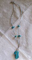 Full view of the necklace showing small tubular silver beads, several natural Kingman turquoise beads, and the Y-shape layout ending in a pendant.