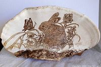 Full view of the original art piece showing the etching of rabbit and butterfly on dried tree outgrowth and part of the metal display stand.