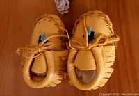 Close-up of soft tan leather baby moccasins with beadwork, showing condition and detail.