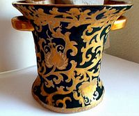 Photo showing the vase's full body with black matte glaze and gold floral and scroll decoration.