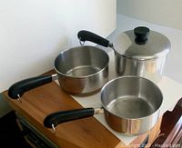 4 vintage Revere Ware saucepans of different sizes with black handles and one with lid.