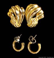 Front view of large folded-style gold-tone Trifari stud earrings and smaller textured gold-filled hoop earrings.