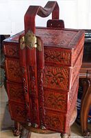 Front view of Chinese wedding basket showing three compartments, wooden carved handle with bronze hardware, and intricate woven wicker with reddish lacquer finish.