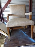 Full frontal view of the brown upholstered armchair showing fabric seat and backrest, wooden legs.