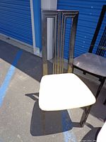 Photo showing one black lacquered wood dining chair with beige fabric seat cushion and vertical slatted back, high gloss finish.