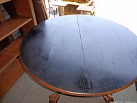 Top view showing dark brown round table surface with extension leaf seam in center.