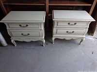 Front view of both white wooden night stands showing two drawers each and curved legs.