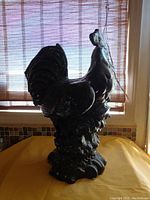 Side angle of large brown ceramic hen sculpture showing feather and base detail.