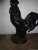 Full side view of the tall dark brown rooster figurine showing standing posture and detailed tail feathers