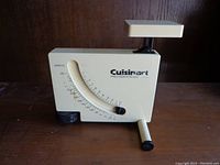 Front view of the vintage Cuisinart cream-colored mechanical portion scale showing the dial, brand name, platform, and balance arm.