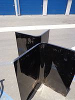 Black lacquered triangular table base with glossy finish, showing surface scratches and wear.