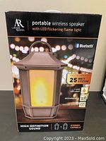 Photo of black box packaging for Acoustic Research portable wireless speaker with LED flickering flame light, details about 25 watt system, rechargeable, weather resistant, 14 hr playtime, stereo capable.
