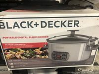 Box front showing BLACK+DECKER branding and image of digital slow cooker with locking lid and control panel.