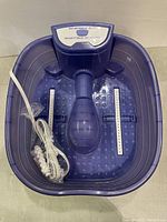Top front view of purple Conair foot spa showing dual foot rollers, central raised section, power cord coiled inside basin