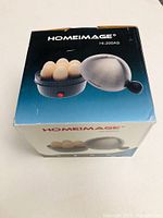 Box showing HomeImage egg boiler with stainless steel lid, black base holding 7 eggs, model HI-200AS