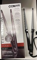 Photo showing boxed Conair multifunctional titanium tourmaline iron with model CS125TTC, highlighting all-in-one styling features (curl, wave, flip, smooth, straighten) and titanium technology details on packaging.