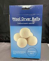 Box front view of new set of five wool dryer balls, showing product name and image of five wool balls, blue packaging with French and English text.